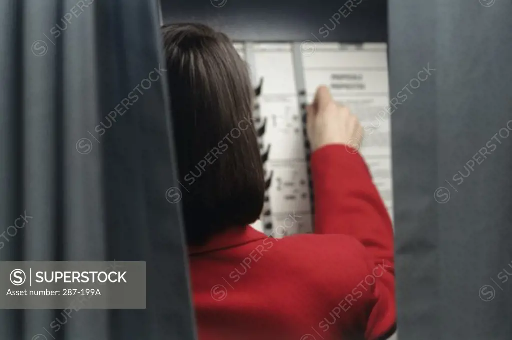 Rear view of a woman voting in a voting booth