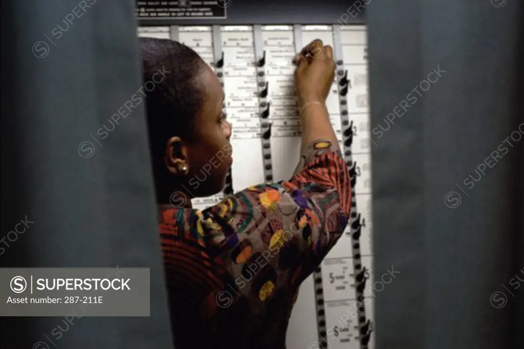 Rear view of a young woman voting in a voting booth