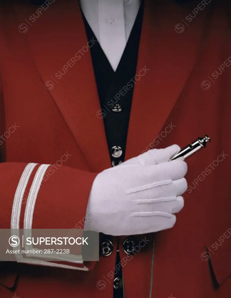 Mid section view of a bellhop holding a whistle