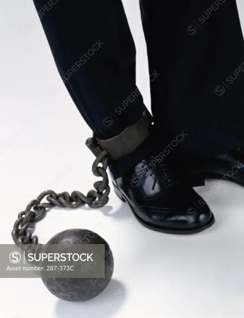 Businessman's leg attached to a ball and chain