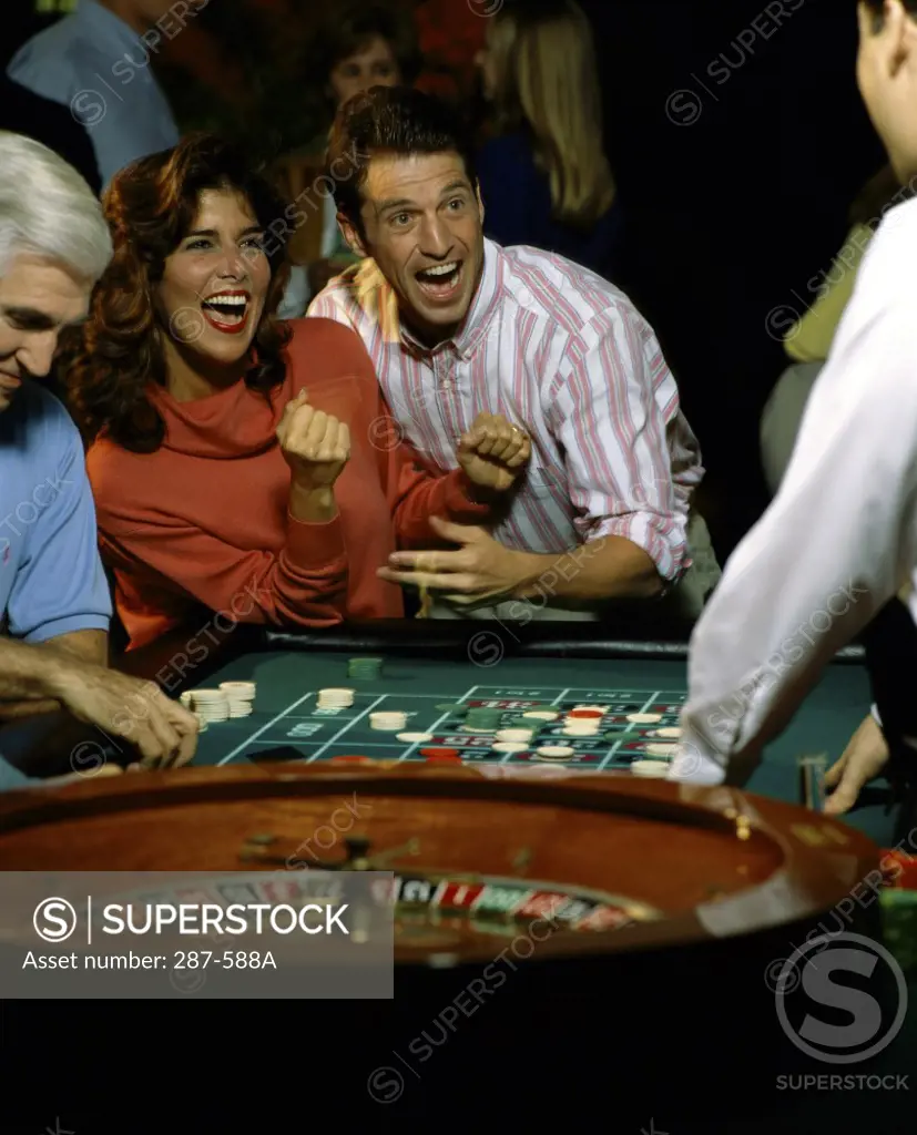 Mid adult couple laughing and looking excited after winning in a casino
