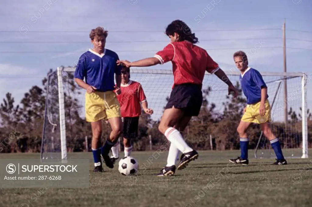 Four young men playing soccer