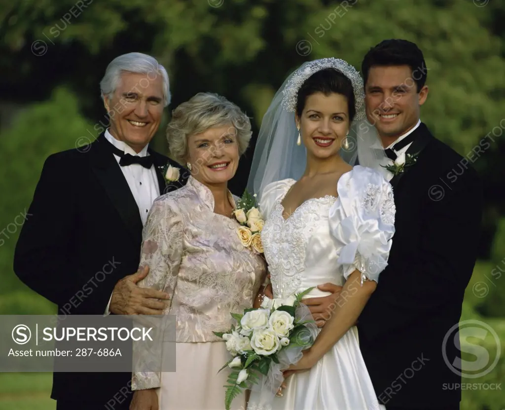Newlywed couple standing with their parents and smiling