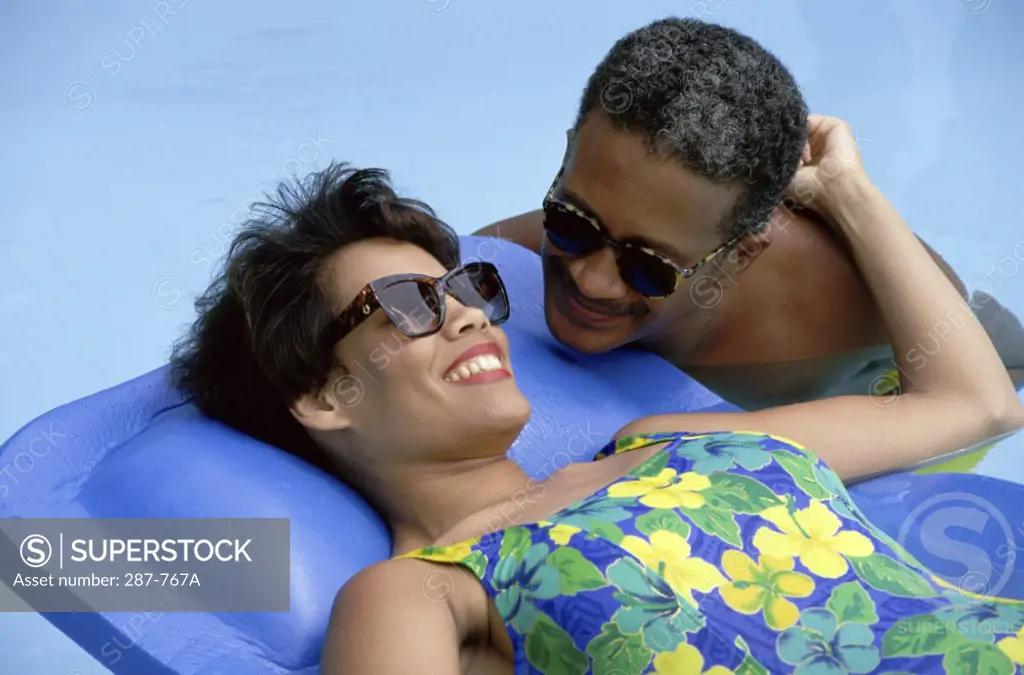 Mature woman lying on a pool raft with a mature man beside her