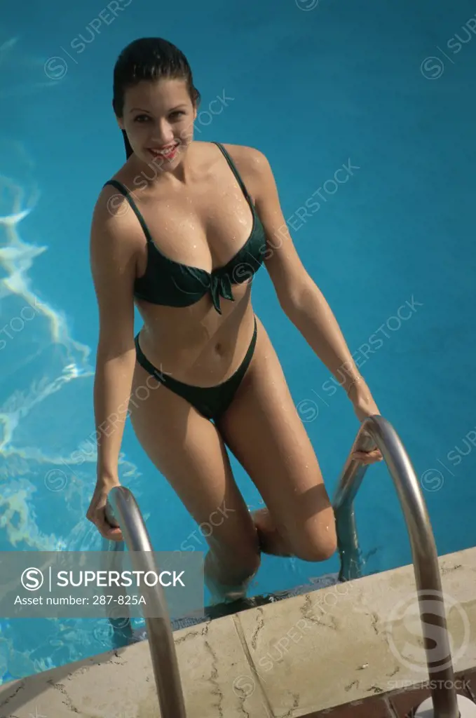 Young woman climbing out of a swimming pool and smiling