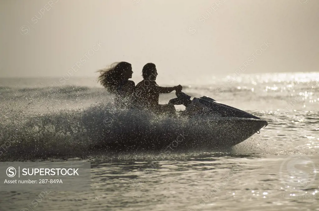 Silhouette of a young couple jet skiing in the sea