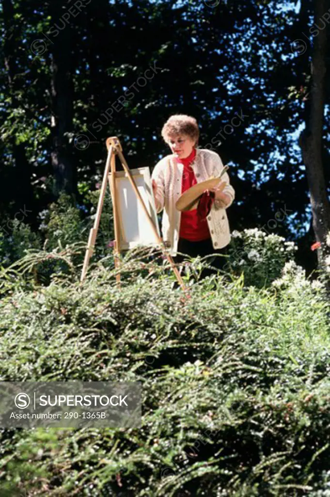 Senior woman painting in a garden