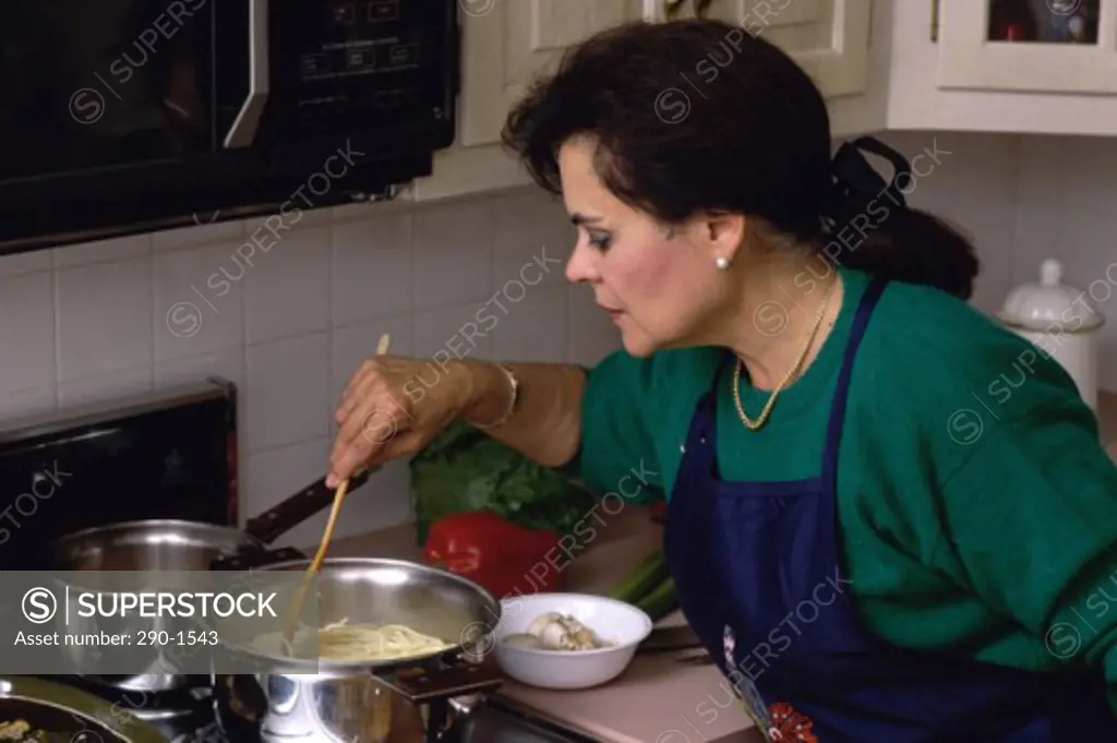 Close-up of a mature woman cooking pasta in a kitchen