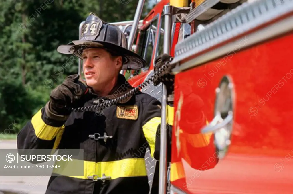 Firefighter standing near a fire engine and talking on a walkie-talkie