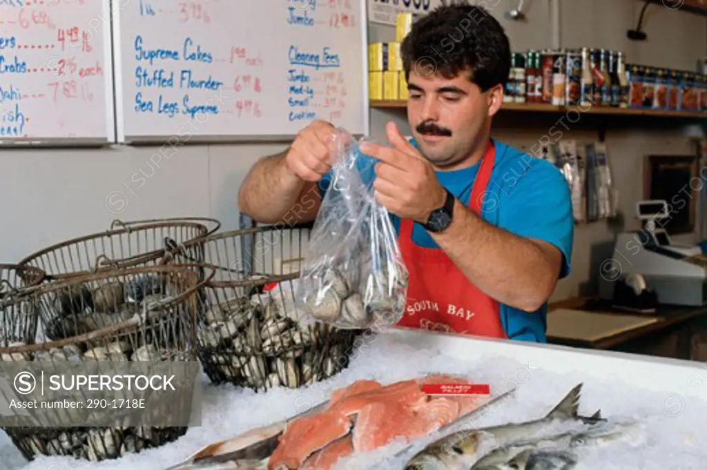 Mid adult man holding a plastic bag filled with seashells in a grocery store