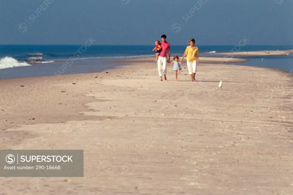 Man and woman with their son and daughter strolling on the beach