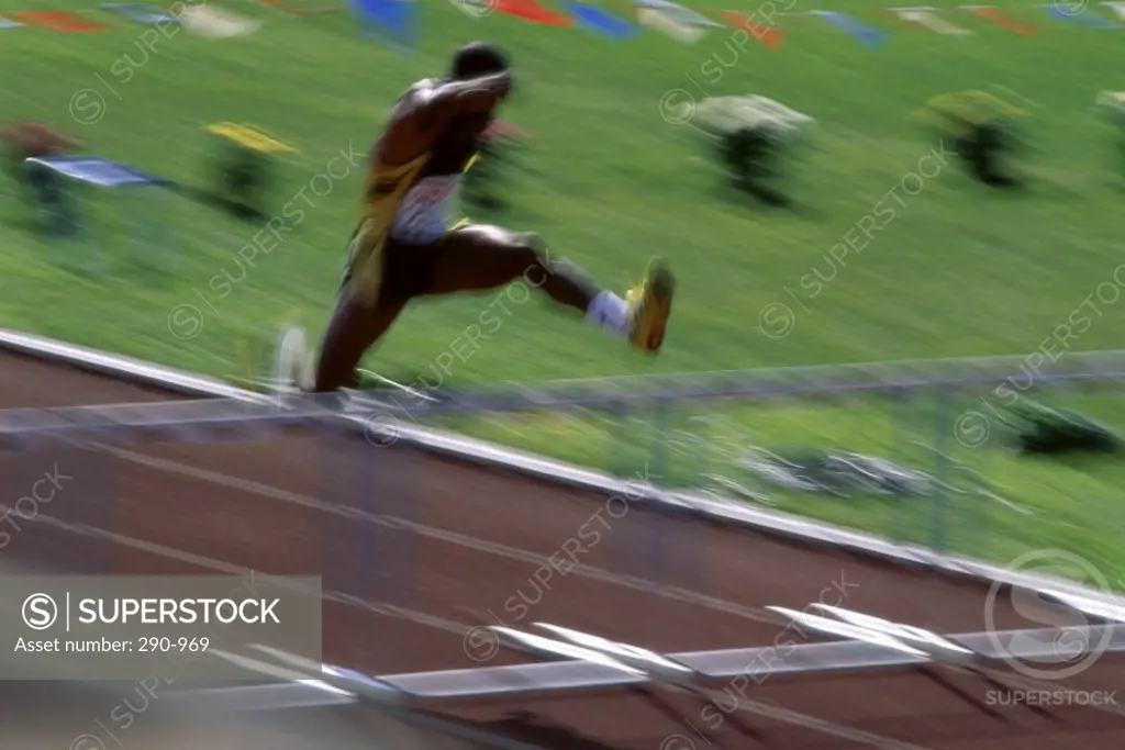 Male athlete jumping over a hurdle