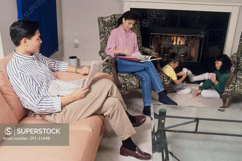 Mid adult couple and their son and daughter sitting in a room near a fireplace