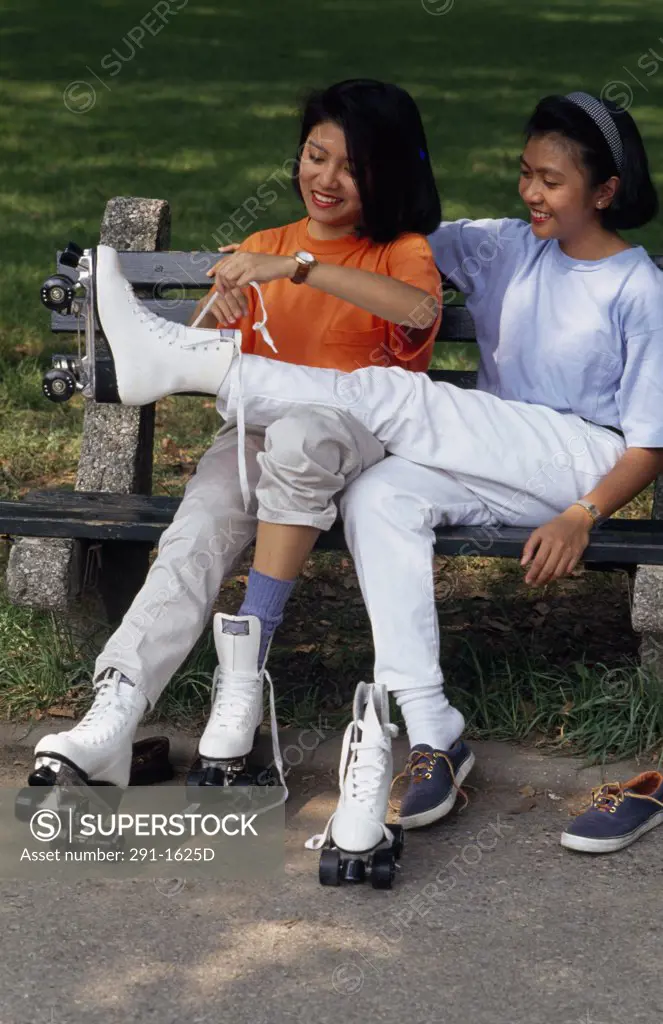 Teenage girl tying the laces of her friend's roller skate