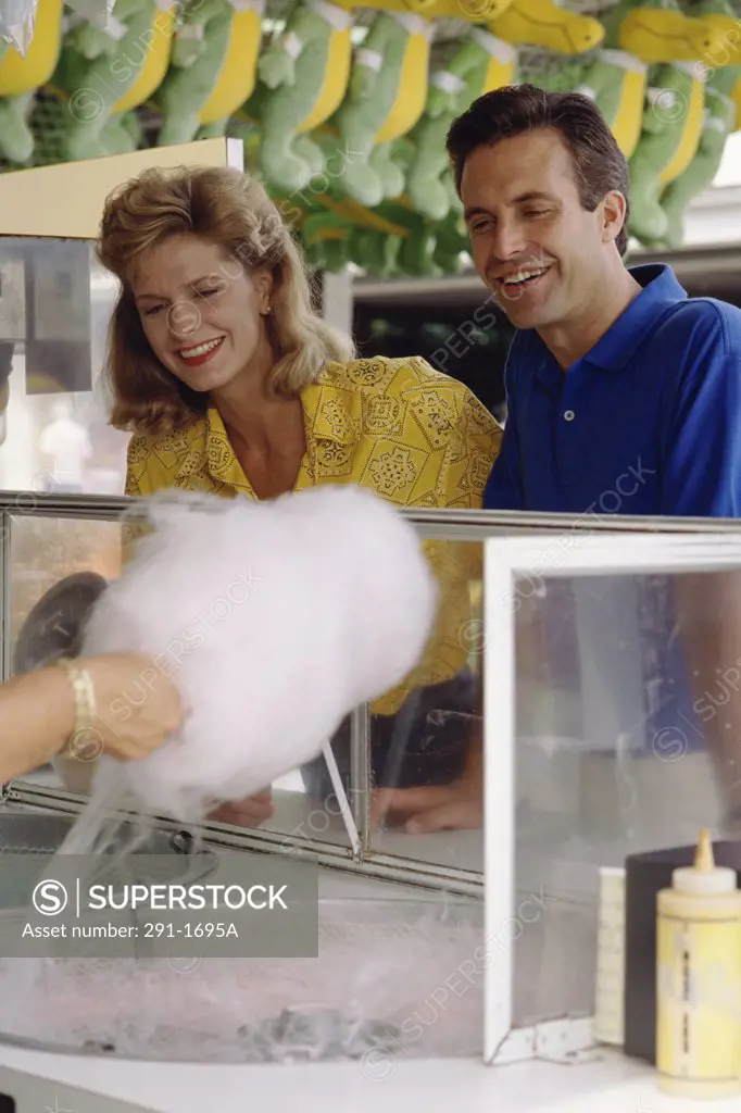 Mid adult couple looking at cotton candy being prepared by a person