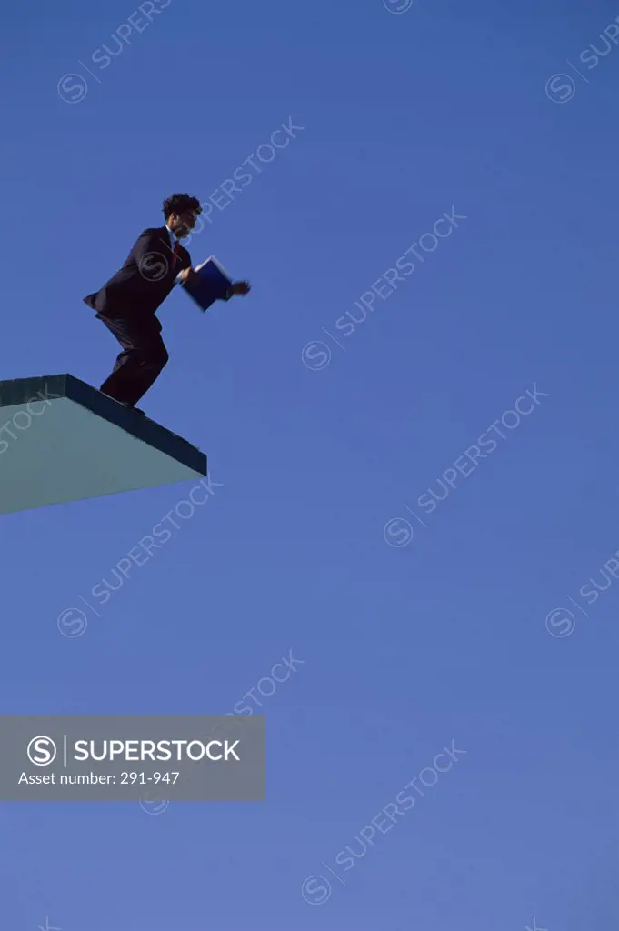 Low angle view of a businessman jumping from a diving board