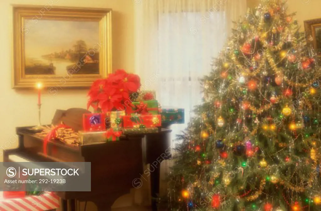 Christmas presents on a piano near a Christmas tree