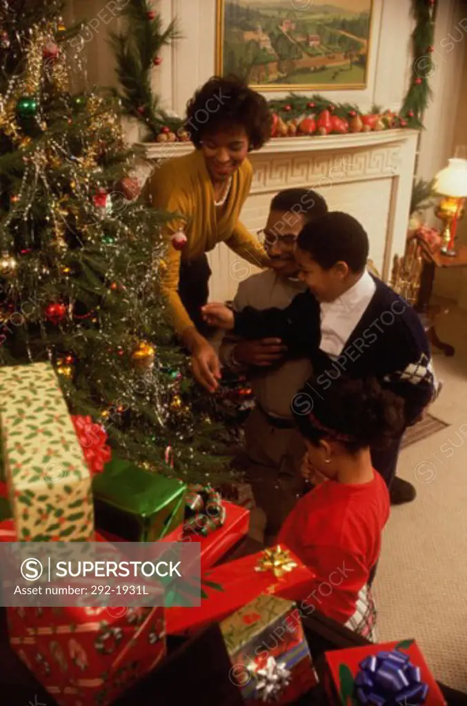 Mid adult couple with their children decorating a Christmas tree