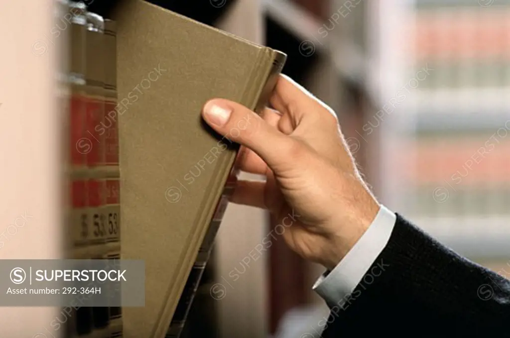 Close-up of a lawyer's hand removing a law book from shelf