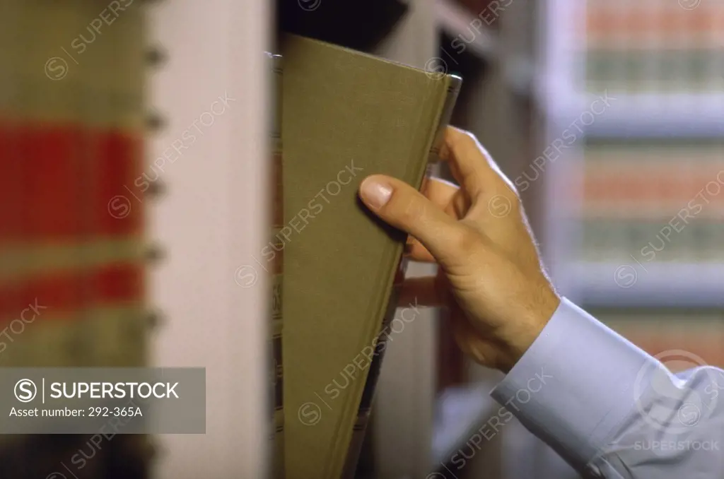 Close-up of a person's hand picking a book in a library