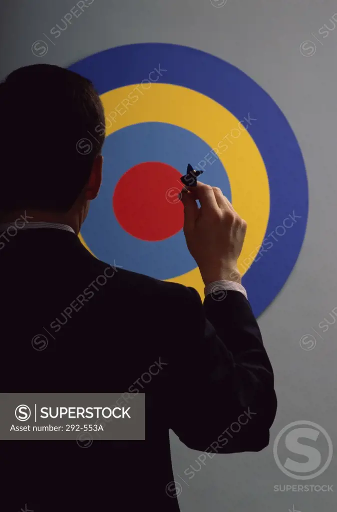 Rear view of a businessman aiming at a bull's eye with a dart