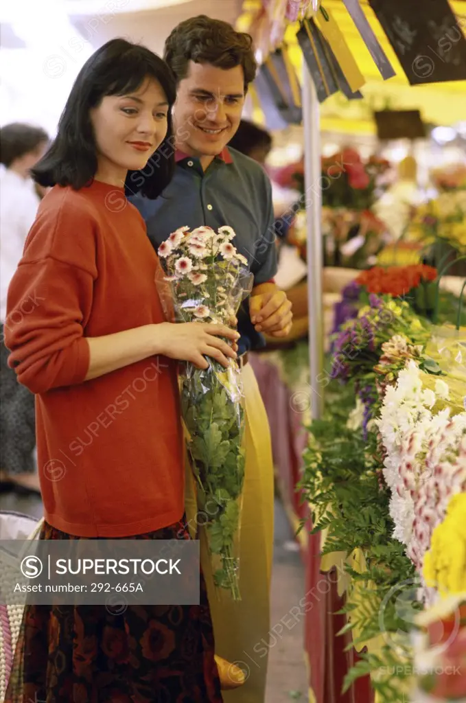 Young couple buying flowers from a flower shop and smiling