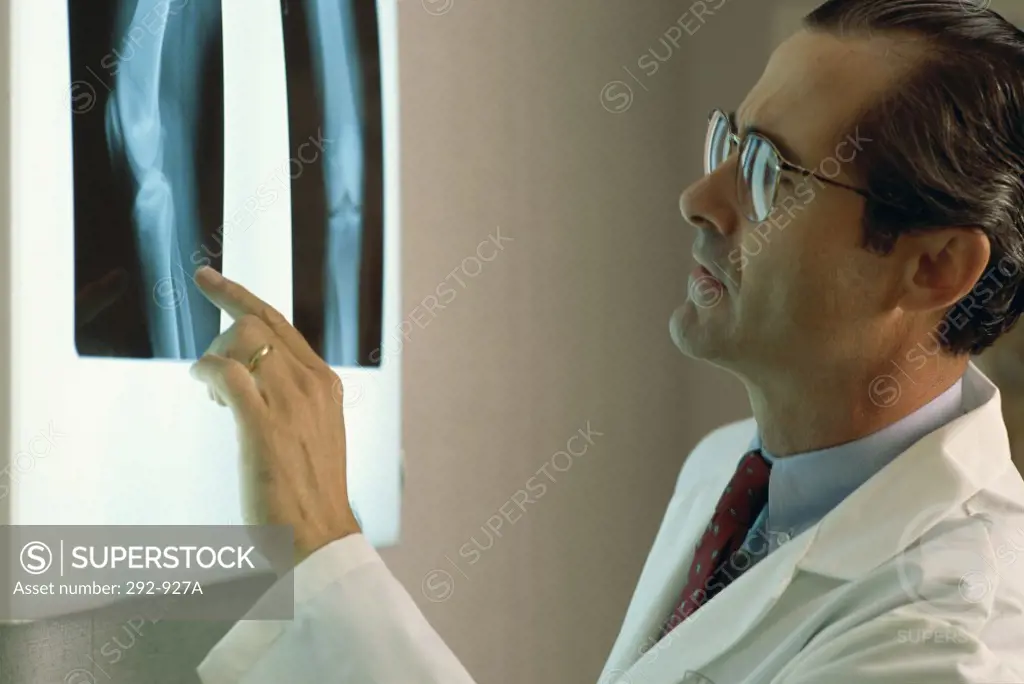 Close-up of a male doctor looking at x-ray reports on a lightbox