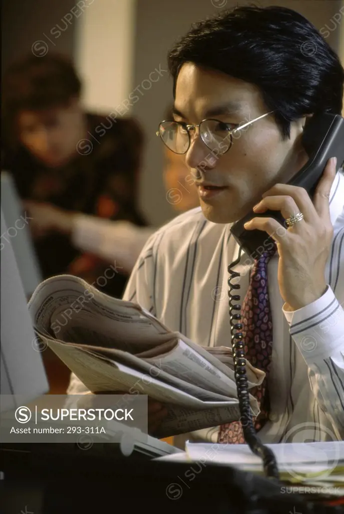 Businessman talking on the telephone and looking at a computer monitor