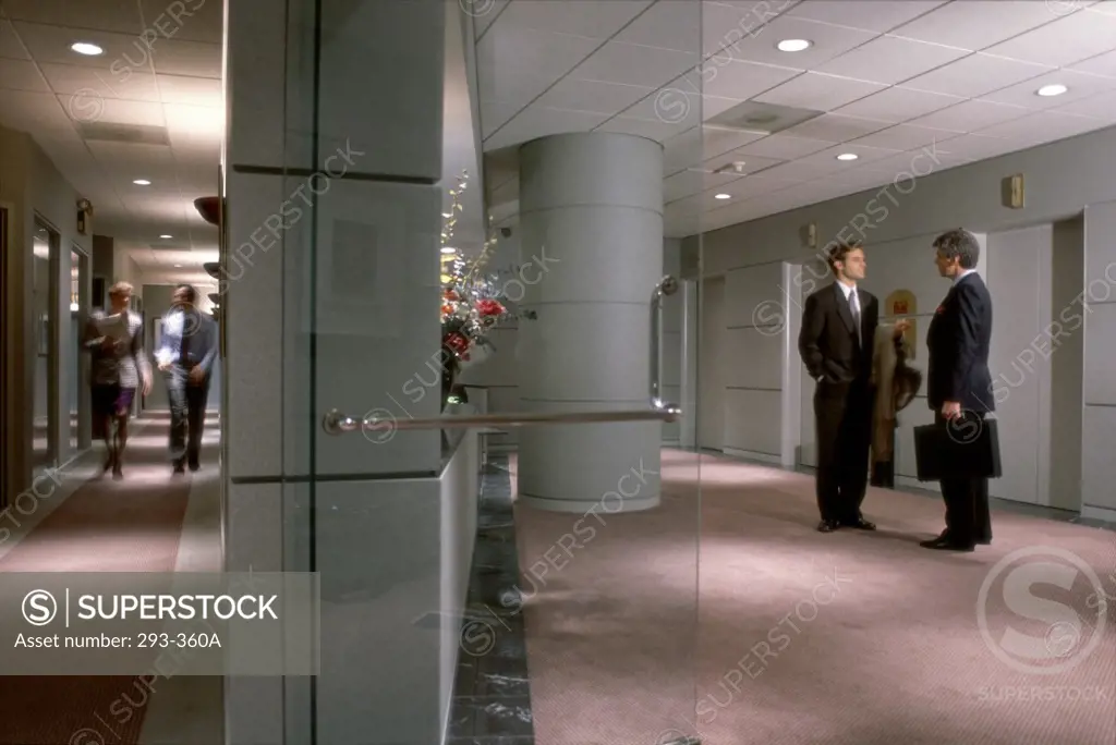 Two businessmen talking to each other in a corridor