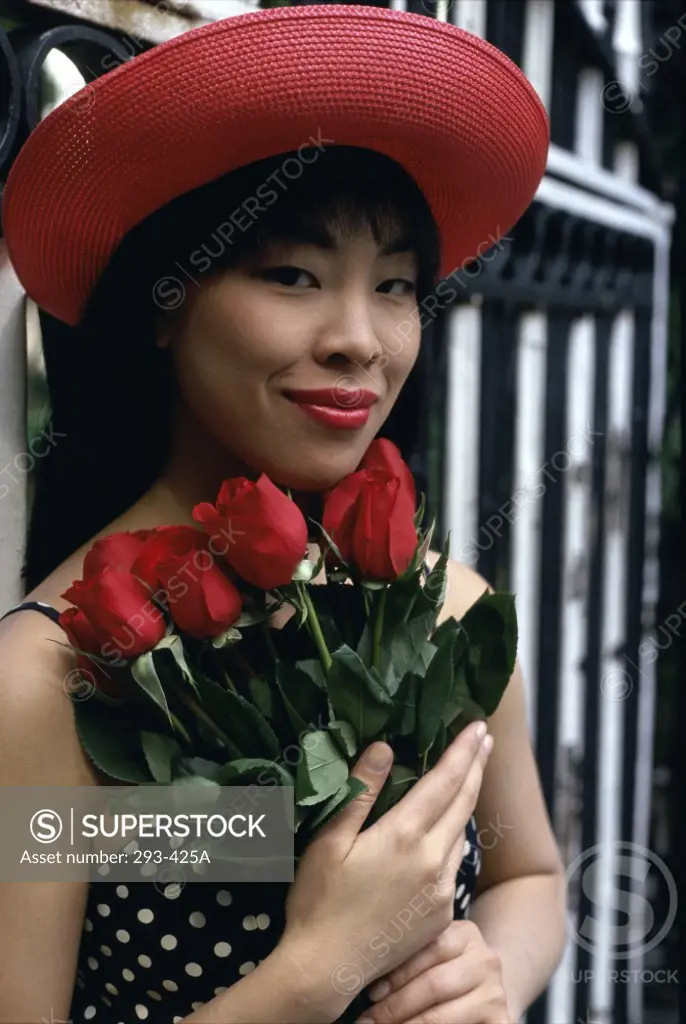 Close-up of a young woman holding a bunch of roses and smiling