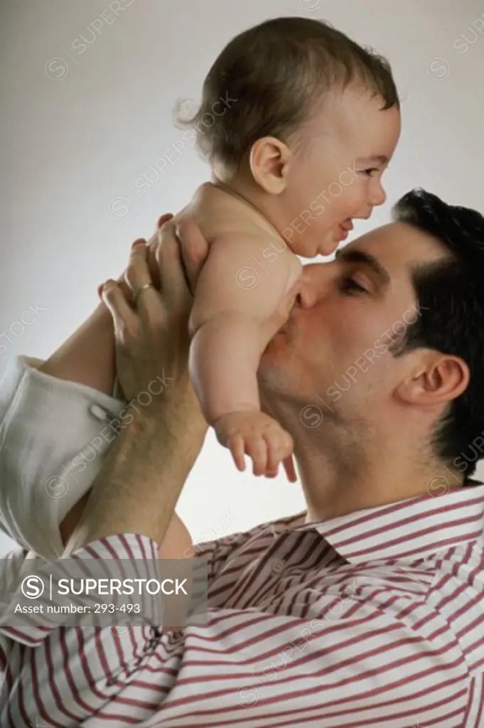 Young man kissing his baby's chest