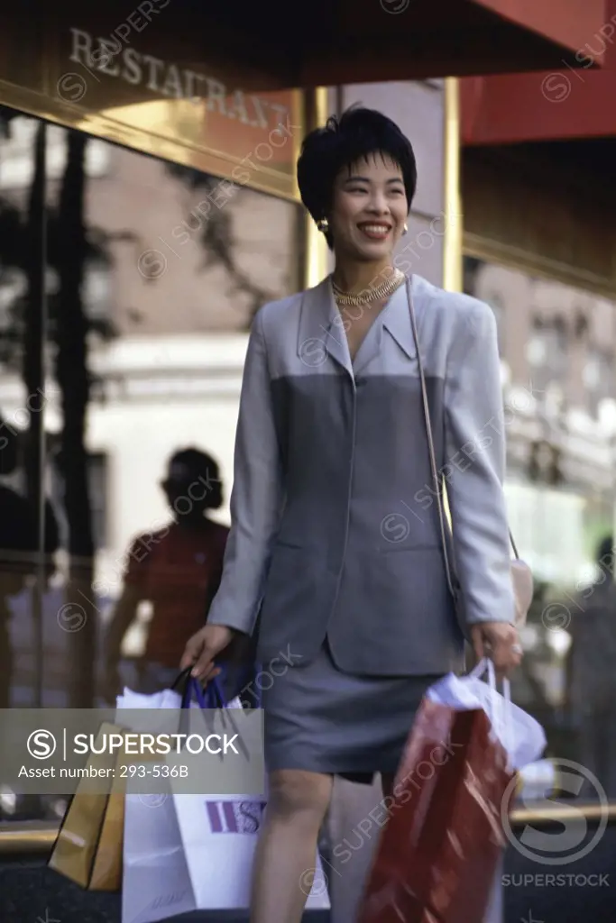 Businesswoman carrying shopping bags and walking in front of a restaurant