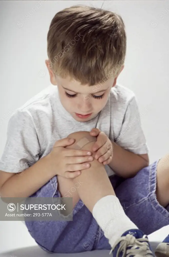Boy looking at an adhesive bandage on his knee