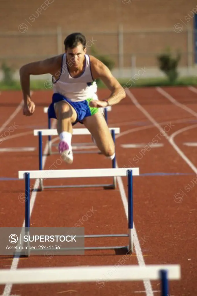 Male athlete jumping over a hurdle