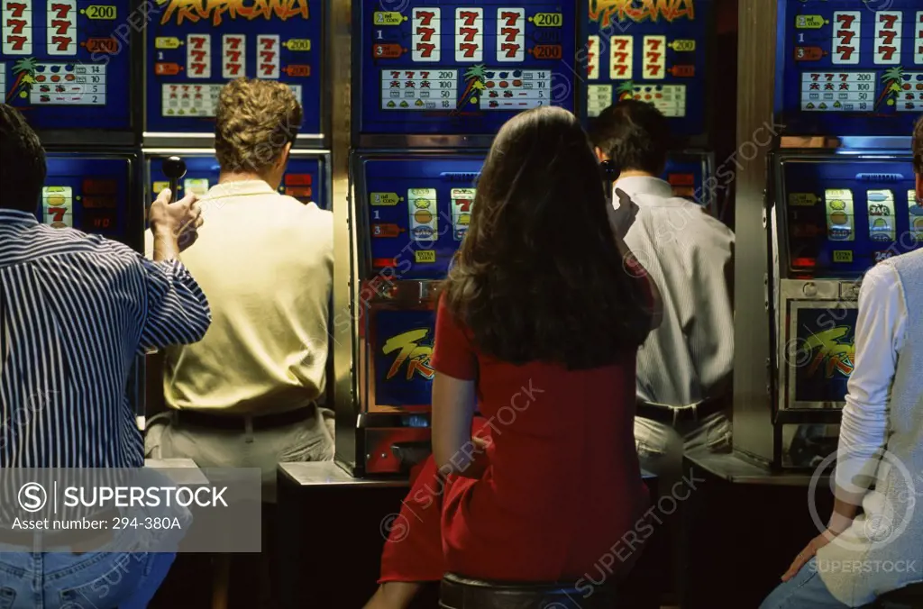 Rear view of women and men playing slot machines in a casino