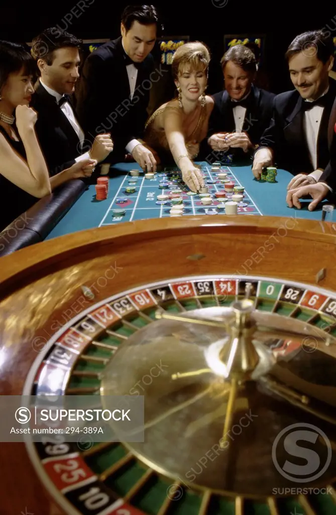 Mid adult women with mid adult men playing at a roulette table in a casino