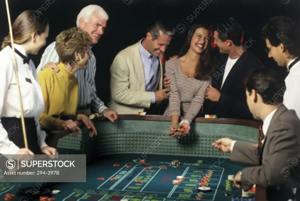 Group of people standing at a gambling table and smiling