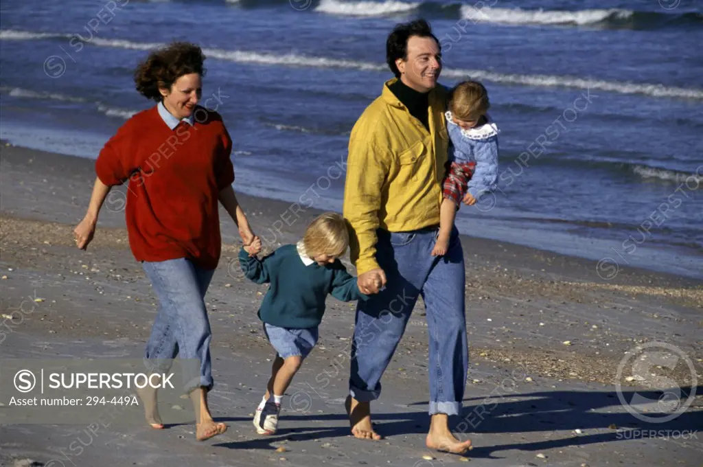 Mid adult couple with their children walking on the beach
