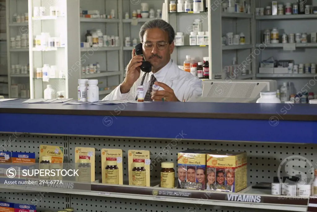 Pharmacist talking on the telephone at a checkout counter in a pharmacy