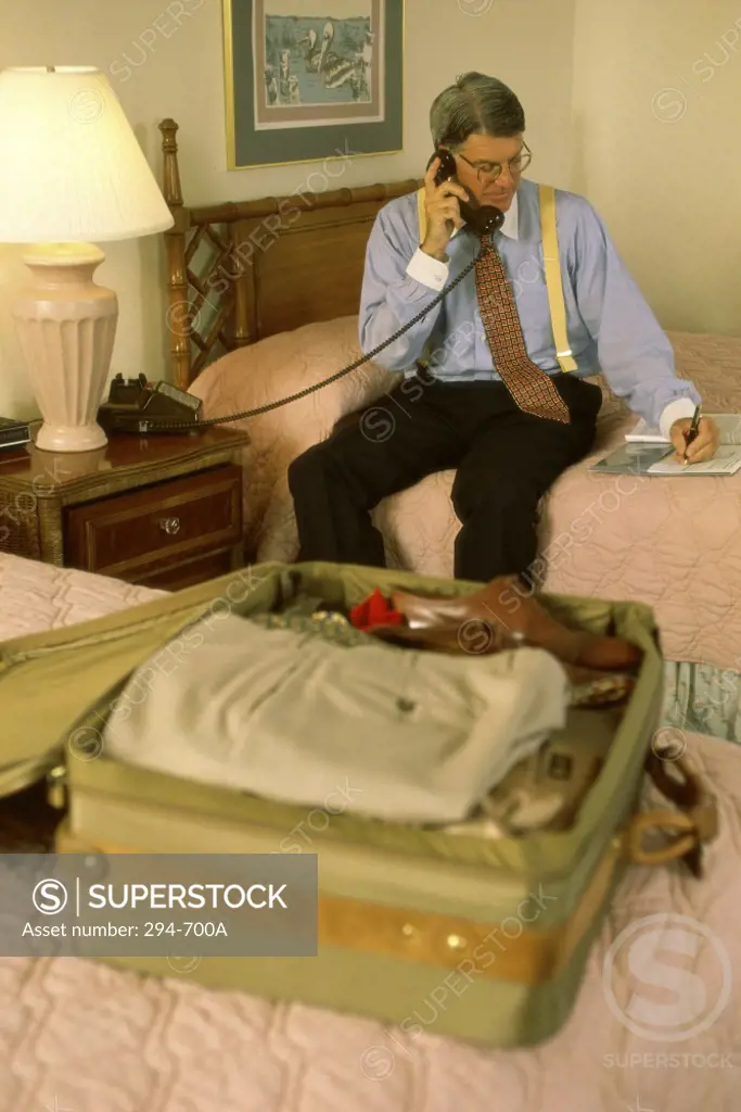 Businessman sitting on the bed and talking on the telephone
