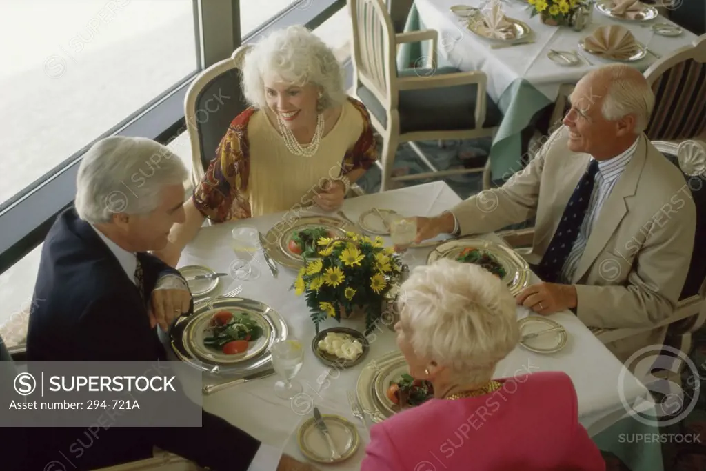 High angle view of two senior couples talking at a dining table