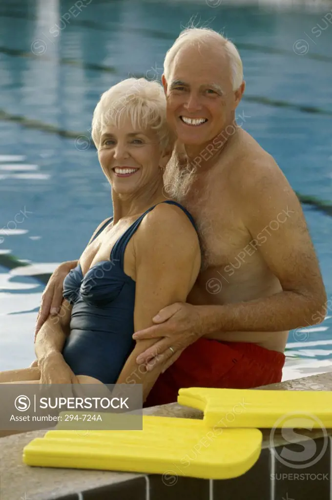 Senior couple sitting at poolside and smiling