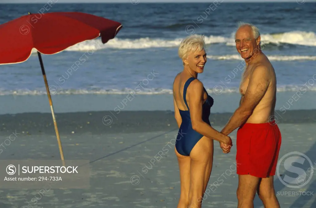 Senior couple standing on the beach and holding hands