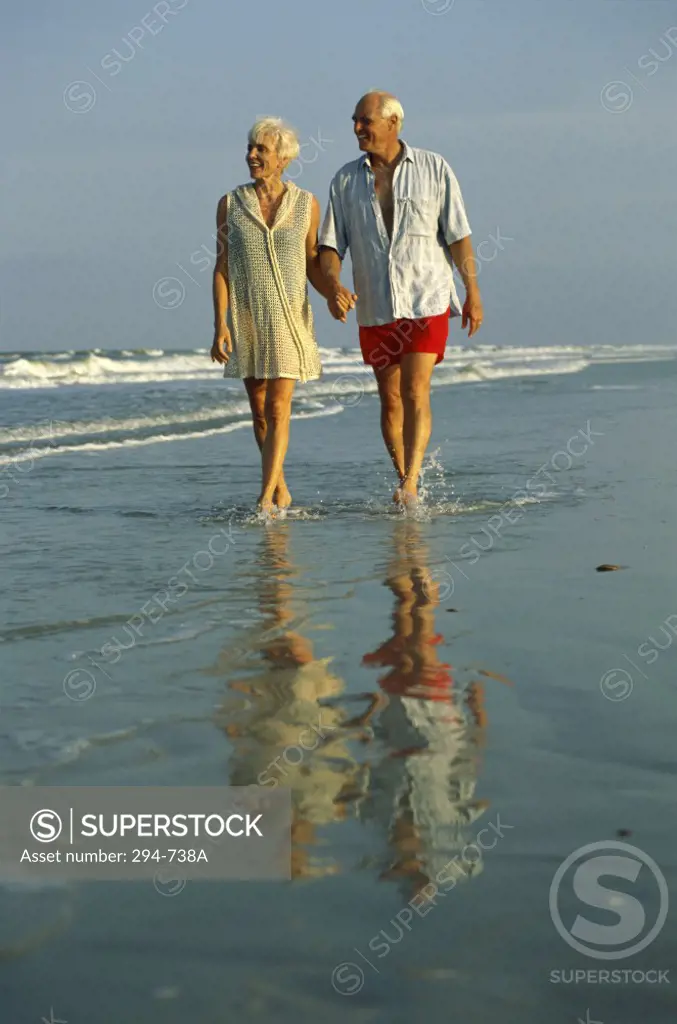Senior couple walking on the beach and holding hands