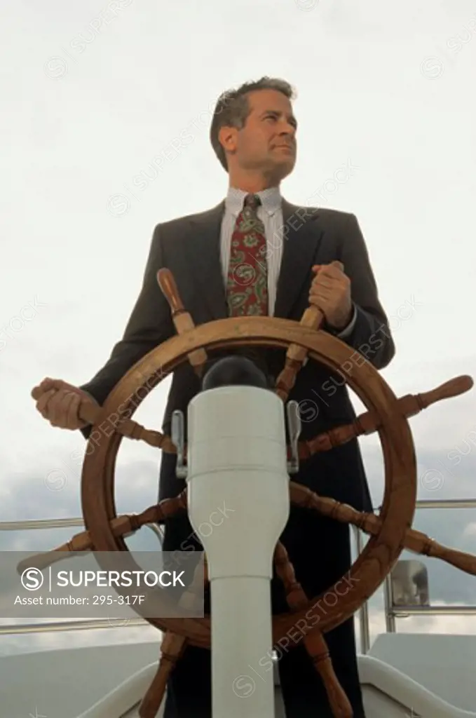 Businessman holding the helm of a boat