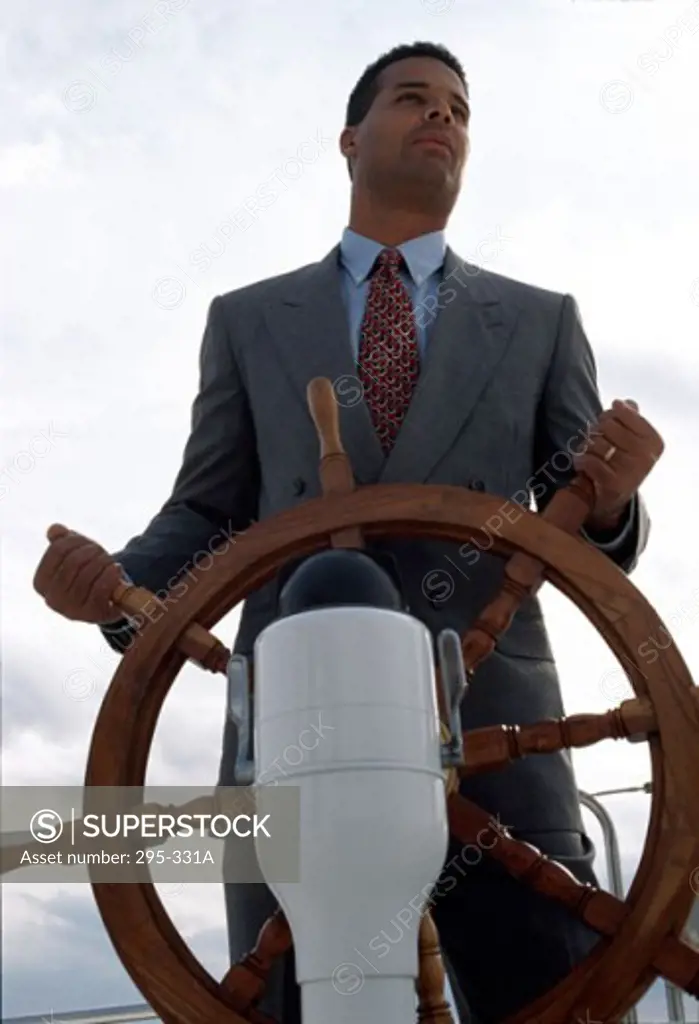 Low angle view of a businessman holding the helm of a boat