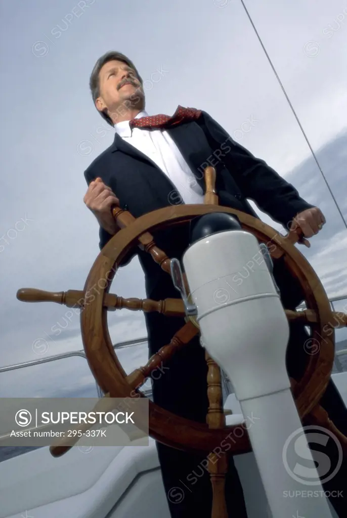 Low angle view of a businessman holding the helm of a sailing ship