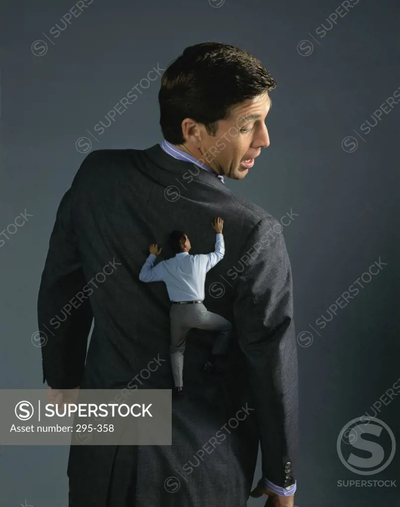 Rear view of a businessman climbing on a coat of another businessman