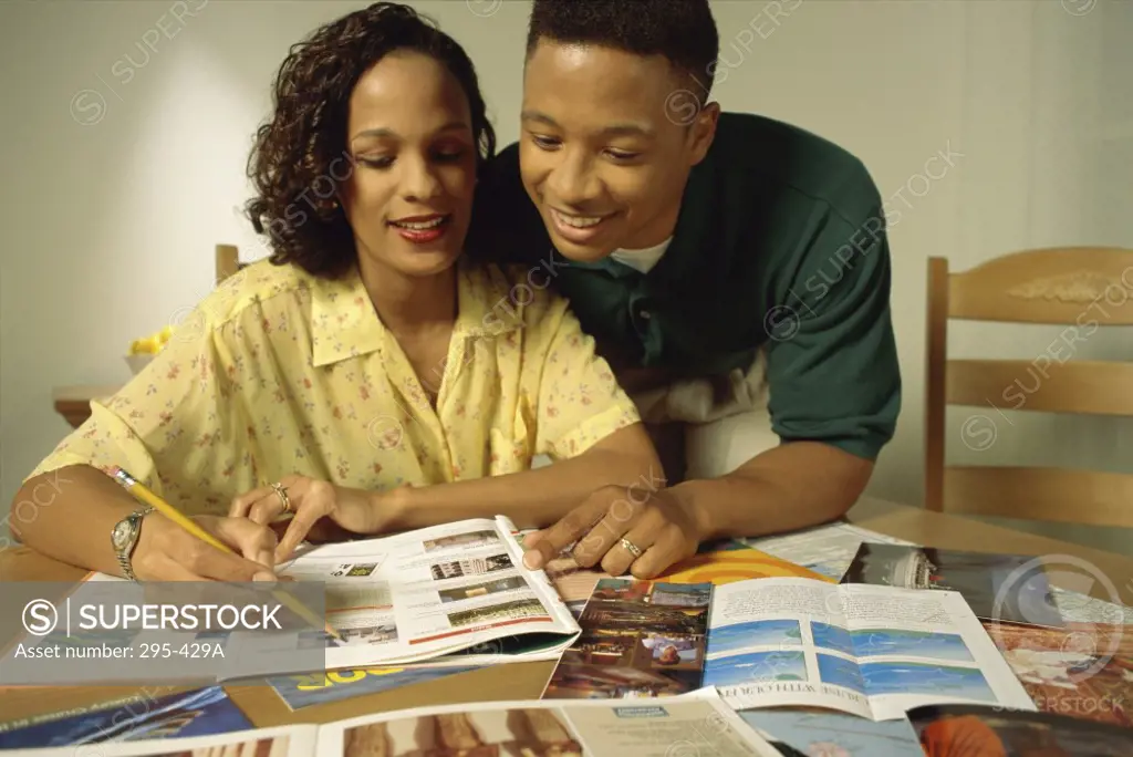Close-up of a young couple looking at a magazine and smiling