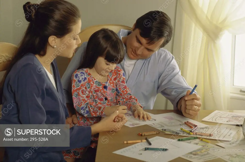 Young couple looking at their daughter drawing a picture